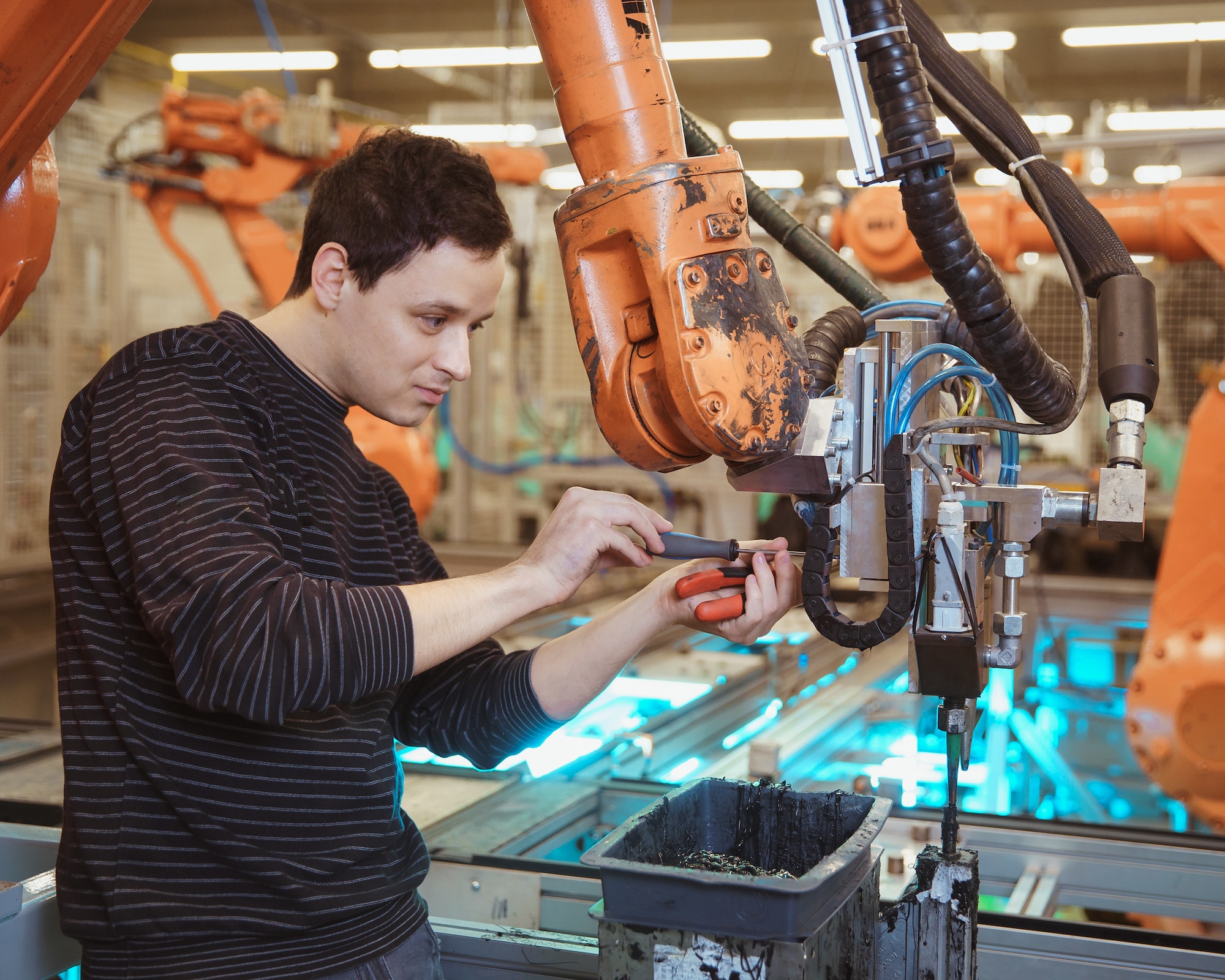 Technical worker performs maintenance robotic arms on the production line