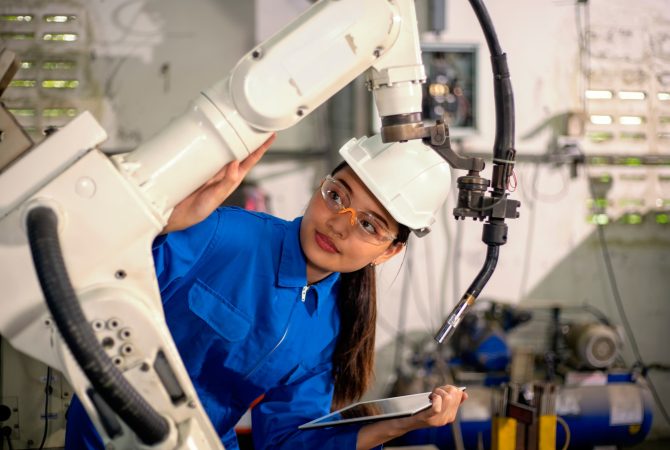Woman mechanic repairing a robot machine.