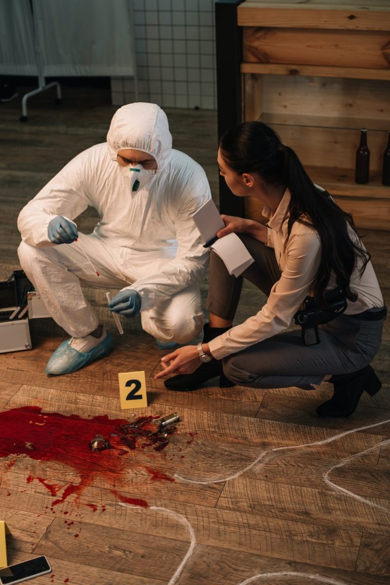 forensic investigator and concentarted female detective taking notes and investigating crime scene